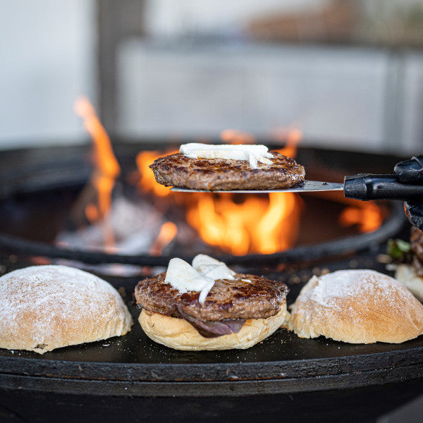 Burger Zubereitung, Wagyu Burger Patty angebraten mit Zwiebeln, Wagyu Burger Set kaufen, Burger Set mit Wagyu-Patties, Wagyu Burger aufgeklappt am Feuer